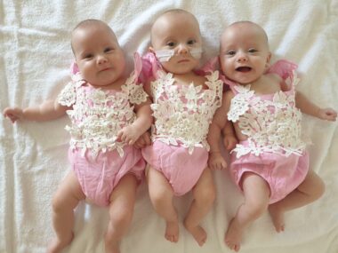 Image of newborn triplet girls wearing matching onesies